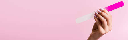 cropped view of woman holding nail file isolated on pink, bannerの写真素材