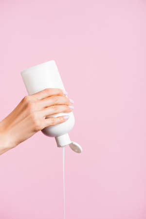 cropped view of woman squeezing lotion isolated on pinkの写真素材