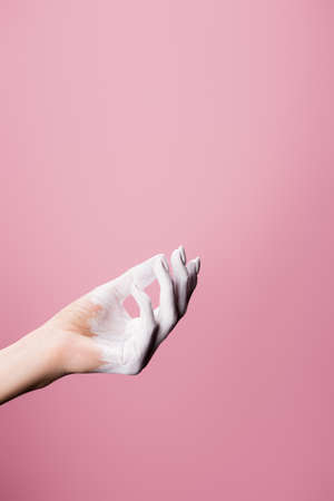 cropped view of white painted hand isolated on pinkの写真素材