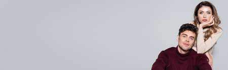 casual young couple in turtleneck jumpers posing isolated on gray, bannerの写真素材