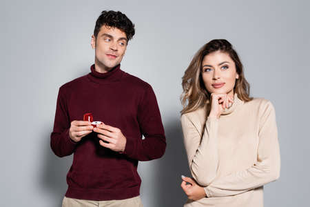 casual young man with engagement ring near woman isolated on gray