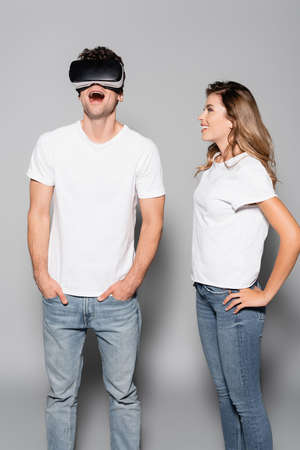 Shocked man in vr headset near woman isolated on grey background.の写真素材