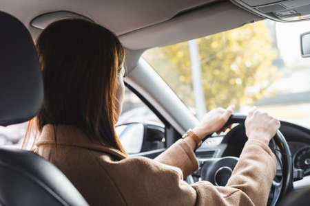 back view of woman steering car on blurred foreground