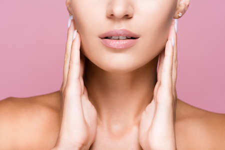 cropped view of beautiful woman with perfect skin touching face isolated on pink backgroundの写真素材