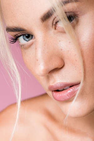 beautiful blonde woman with freckles isolated on pink backgroundの写真素材