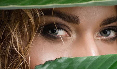 closeup of blonde woman with wet hair and green leavesの写真素材