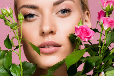 beautiful blonde woman with rose bouquet isolated on pink backgroundの写真素材