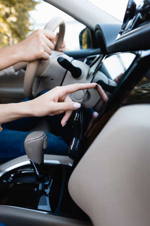 Cropped view of woman using audio system while husband driving auto