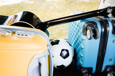Football, suitcases and acoustic guitar in car trunk