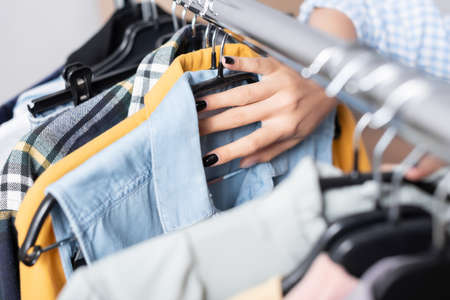 Cropped view of volunteer holding clothes on hanging rack on blurred foreground in charity centerの写真素材