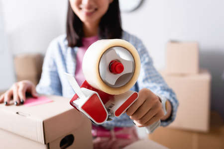 Close up view of scotch dispenser in hands of female volunteer on blurred background in charity...