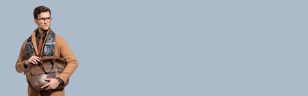 stylish man in winter coat holding leather briefcase isolated on gray, bannerの写真素材