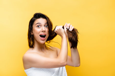 shocked beautiful woman with wet hair isolated on yellowの写真素材