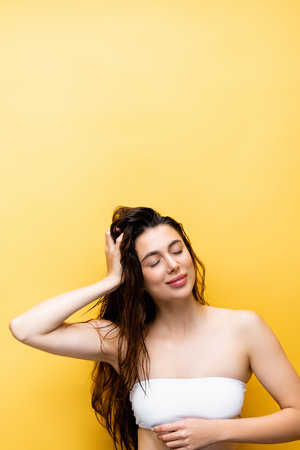 smiling beautiful woman with wet hair isolated on yellowの写真素材