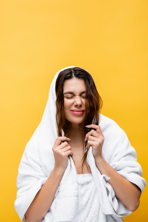 beautiful woman with closed eyes, wet hair and towel isolated on yellowの写真素材