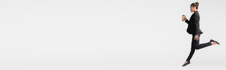 side view of african american businesswoman performing ballet with paper cup isolated on gray, bannerの写真素材