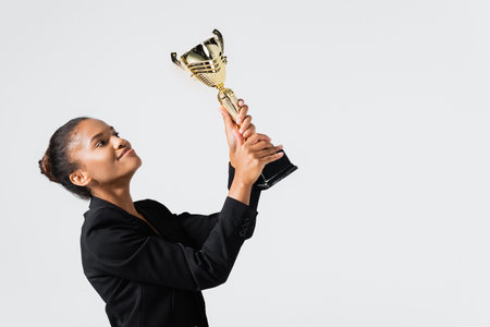smiling african american businesswoman with golden cup isolated on grayの写真素材