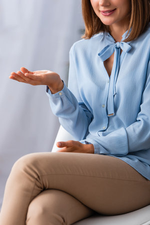 Cropped view of female psychologist gesturing while sitting on chair in officeの写真素材