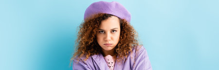 displeased woman in beret puffing cheeks on blue, bannerの写真素材