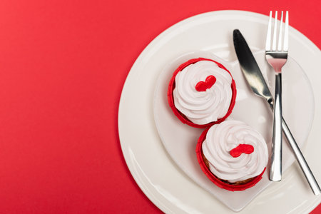 top view of cupcakes on plate with cutlery on red backgroundの写真素材