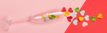 top view of champagne glass with hearts on pink and red background, banner