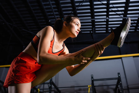 low angle view of sportswoman stretching leg while training in gymの写真素材