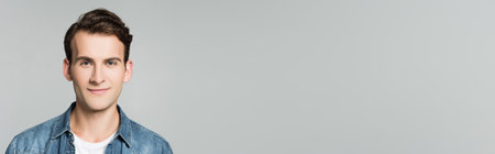 Young man smiling at camera isolated on gray, bannerの写真素材