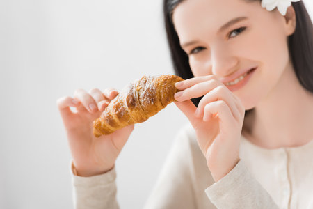 croissant in hands of happy woman with vitiligo on blurred backgroundの写真素材