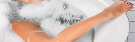 Top view of wet leg of woman in bathtub with foam, banner