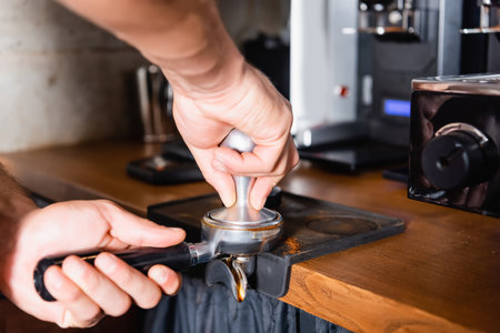 cropped view of barista pressing ground coffee in portafilterの写真素材