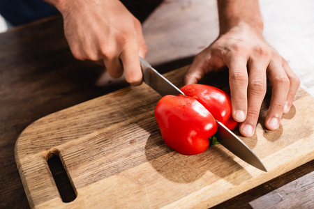 Cropped view of man cutting bell pepper on wooden cutting boardの写真素材