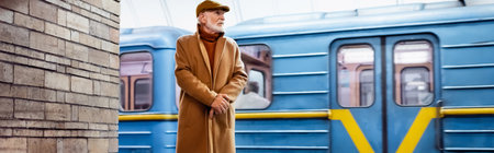 aged man in autumn clothes standing on metro platform with train on background, bannerの写真素材