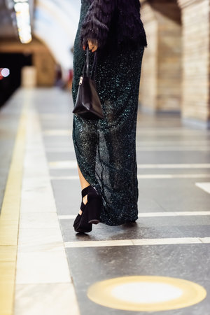 cropped view of elegant woman in long black dress walking along subway platform
