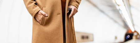 partial view of aged man in autumn clothes standing with hand in pocket on metro platform, bannerの写真素材