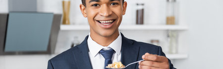 cheerful african american businessman holding spoon with corn flakes, banner