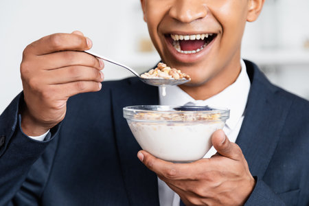 cropped view of amazed african american businessman holding bowl with corn flakes and milkの写真素材