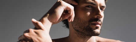 Shirtless man with hand near head looking at camera isolated on gray, bannerの写真素材