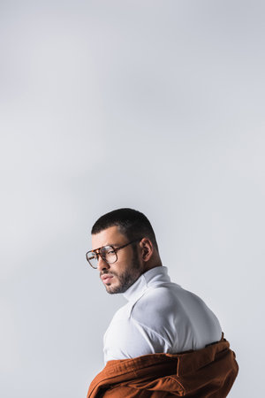 Stylish man in white turtleneck and jacket looking away isolated on grayの写真素材