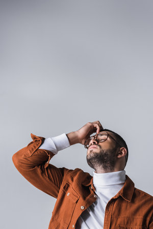 Bearded man in casual clothes standing with closed eyes isolated on grayの写真素材