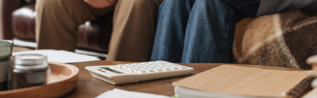 cropped view of elderly couple sitting near table with white calculator at home on blurred background, bannerの写真素材