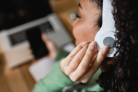 african american woman listening podcast and touching headphones