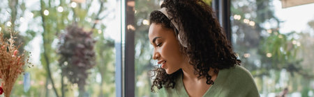 african american woman listening podcast in wireless headphones, banner