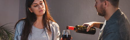 husband pouring red wine into glass of wife, bannerの写真素材