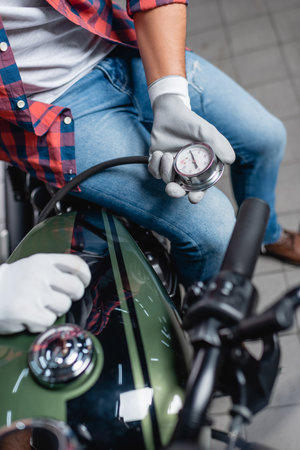 selective focus of manometer in hands of technician measuring air pressure in tire of motorcycleの写真素材