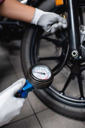selective focus of manometer in hands of mechanic measuring air pressure in tire of motorcycleの写真素材