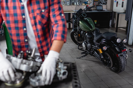 selective focus of motorcycle near mechanic and disassembled gearbox on blurred foregroundの写真素材