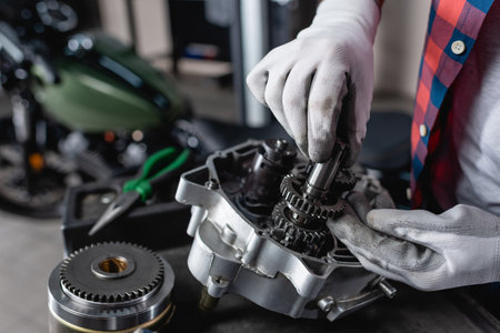 partial view of technician in gloves examining disassembled motorbike gearboxの写真素材