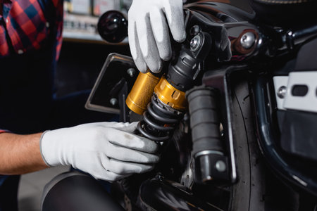 cropped view of mechanic checking shock absorber of motorcycle in workshopの写真素材