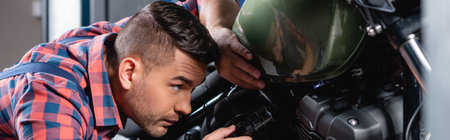 mechanic holding flashlight while checking fuel tank of motorcycle, banner