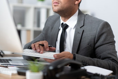 cropped view of trader typing on keyboard in office, blurred foregroundの写真素材